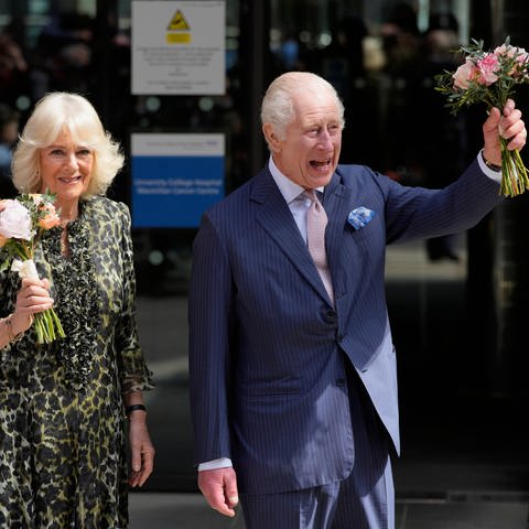 König Charles III. und seine Frau Königin Camilla besuchen gut gelaunt eine Krebszentrum. Beide tragen kleine Sträuße in der Hand. (Foto: picture-alliance / Reportdienste, picture alliance/dpa/AP | Kin Cheung)